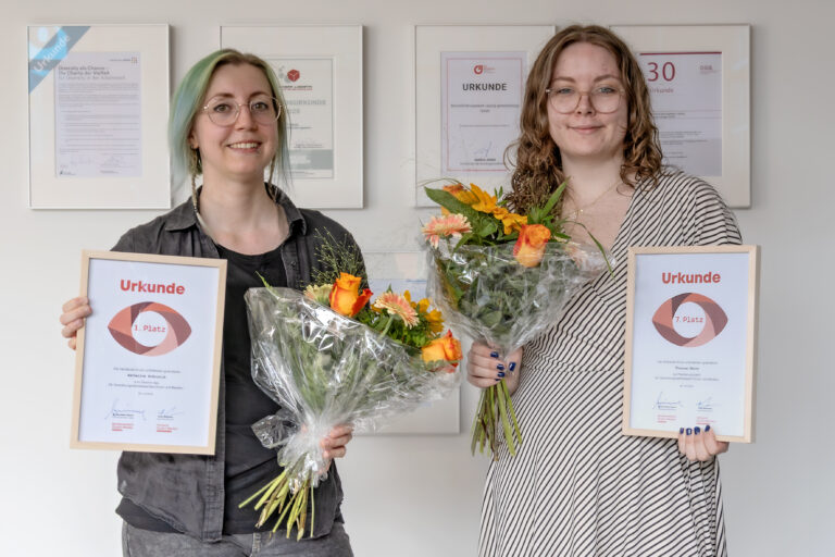 Zwei junge Mediengestalterinnen bekommen Urkunden und Blumen überreicht