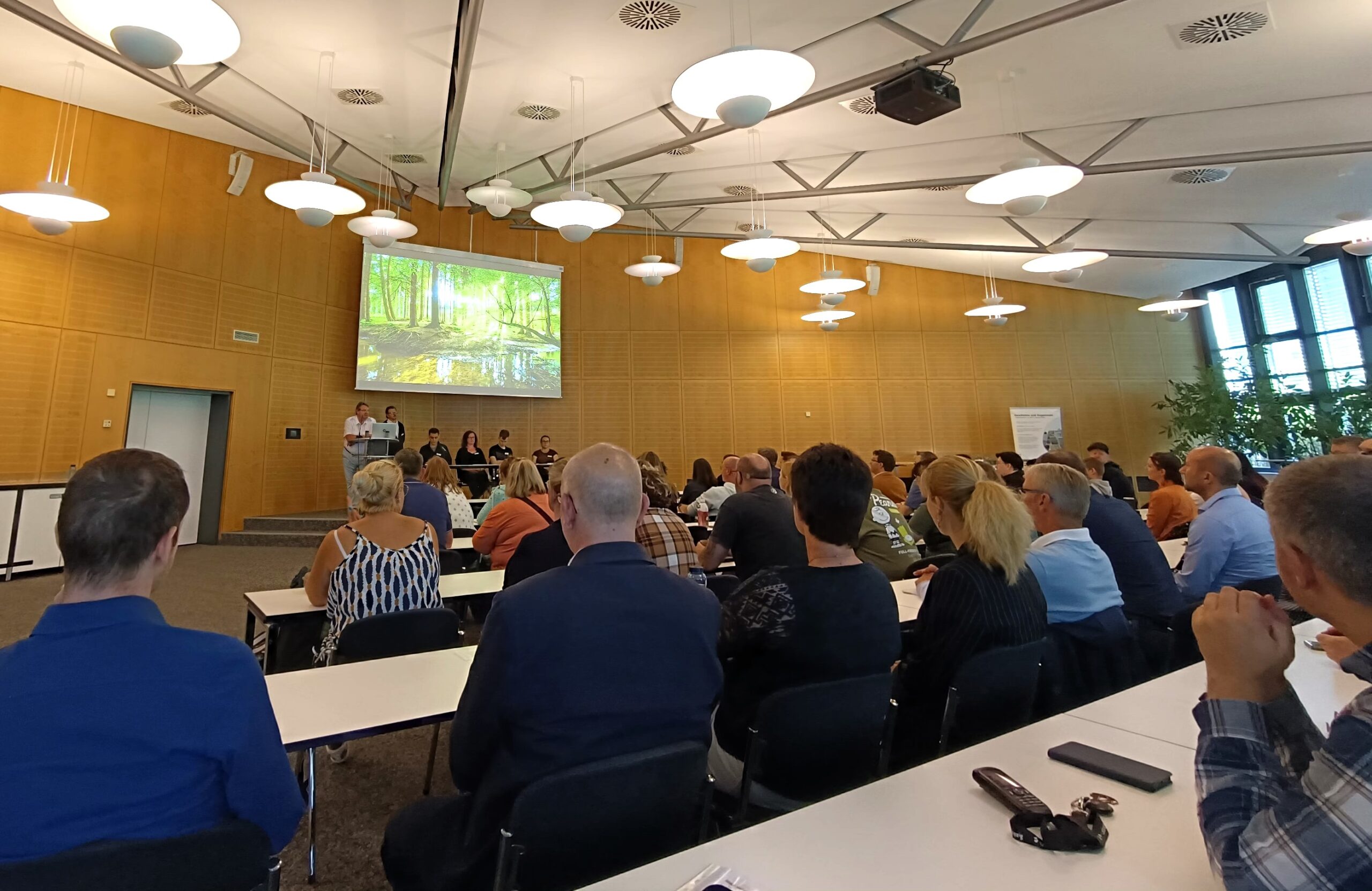Eine Gruppe Menschen sitzt in einem Konferenzsaal und hört zu.