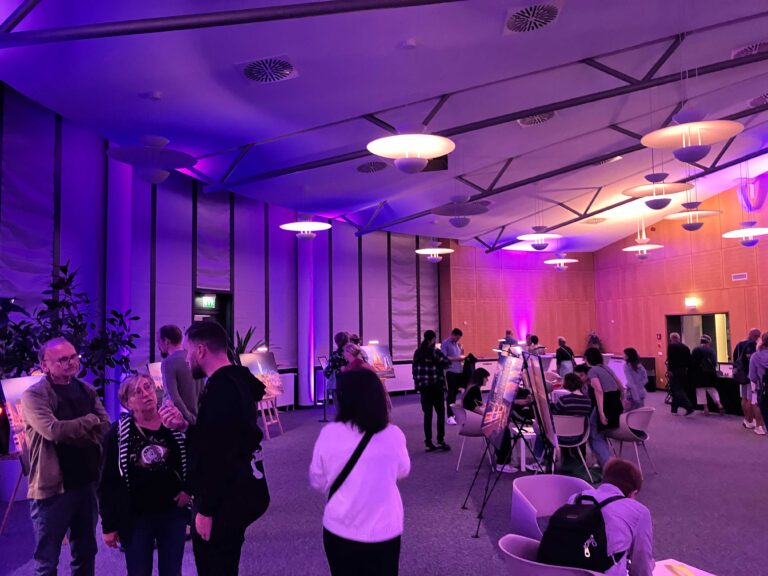 Lila ausgeleuchteter Raum mit einer Fotoausstellung und Menschen die sich diese anschauen.