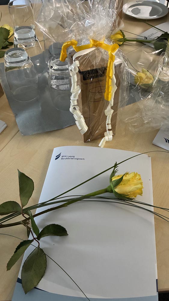 Symbolbild: Eine gelbe Rose liegt auf einer Zeugnismappe