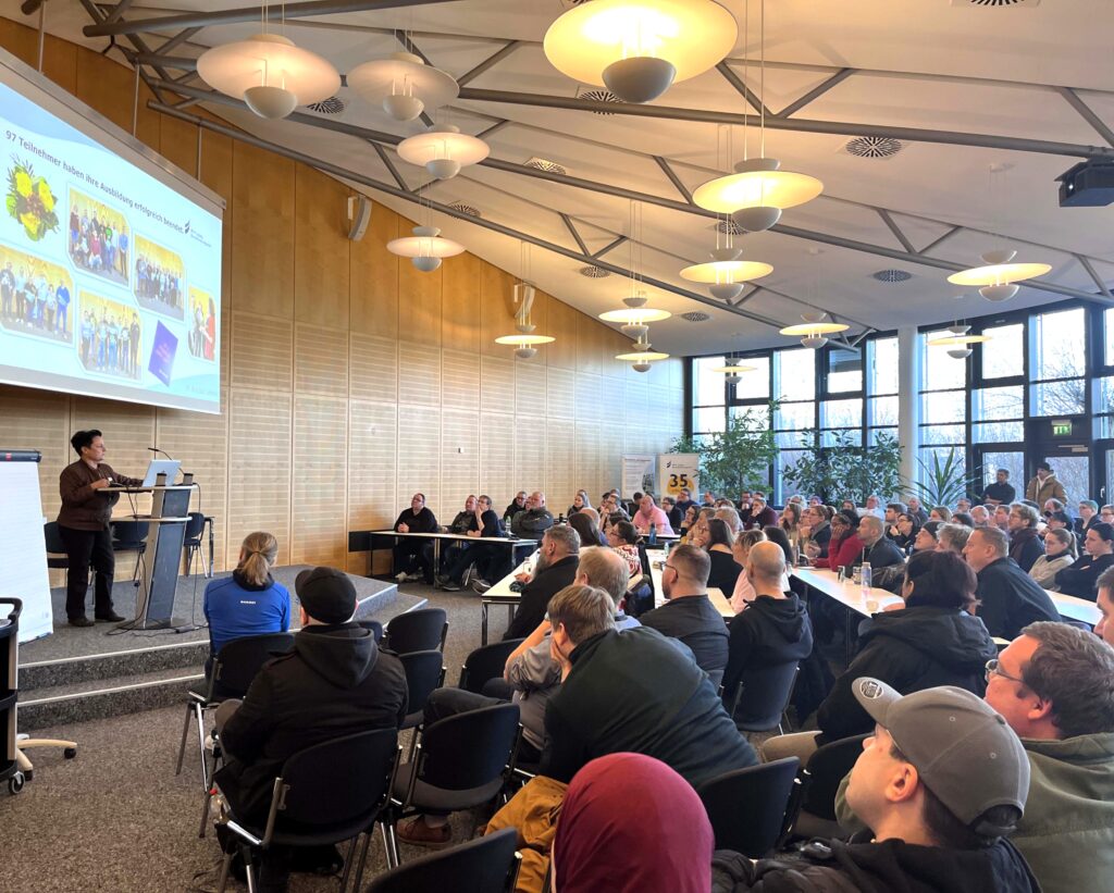 Die pädagogische Leiterin begrüßt in der Aula die neuen Teilnehmenden.