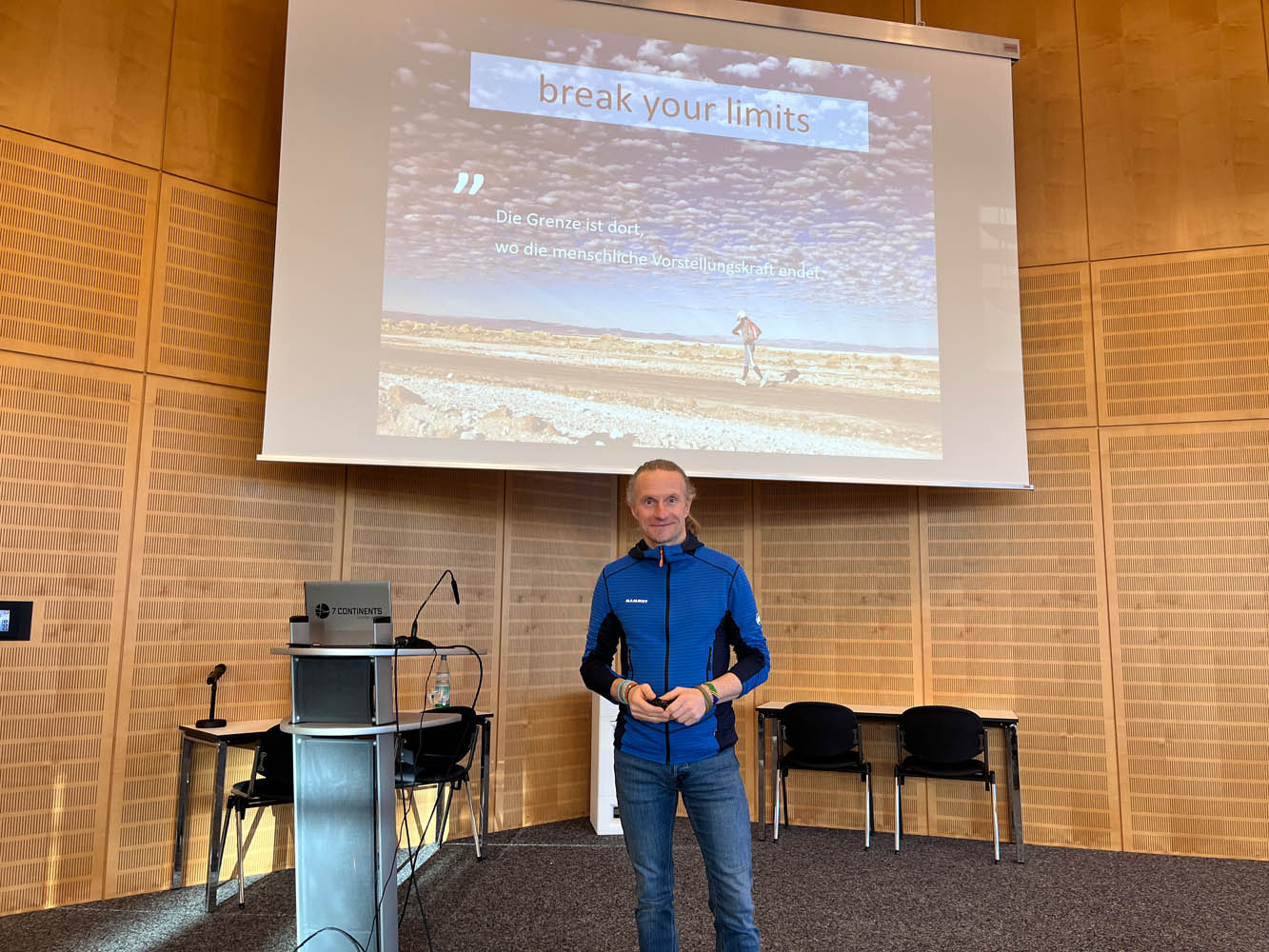 Norman Bücher steht auf der Bühne im BFW Leipzig, im Hintergrund ist seine Präsentation zu sehen.